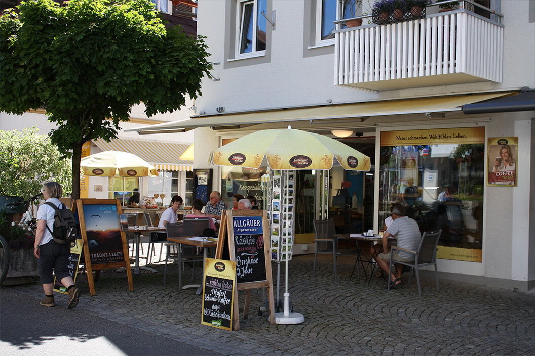 kleiner Käseverkaufsladen in Oberstdorf mit einer schattigen Terrasse unter Bäumen