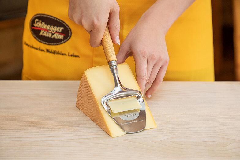 Ein Käsehobel um dünne Scheiben von einem Stück Käse zu schneiden