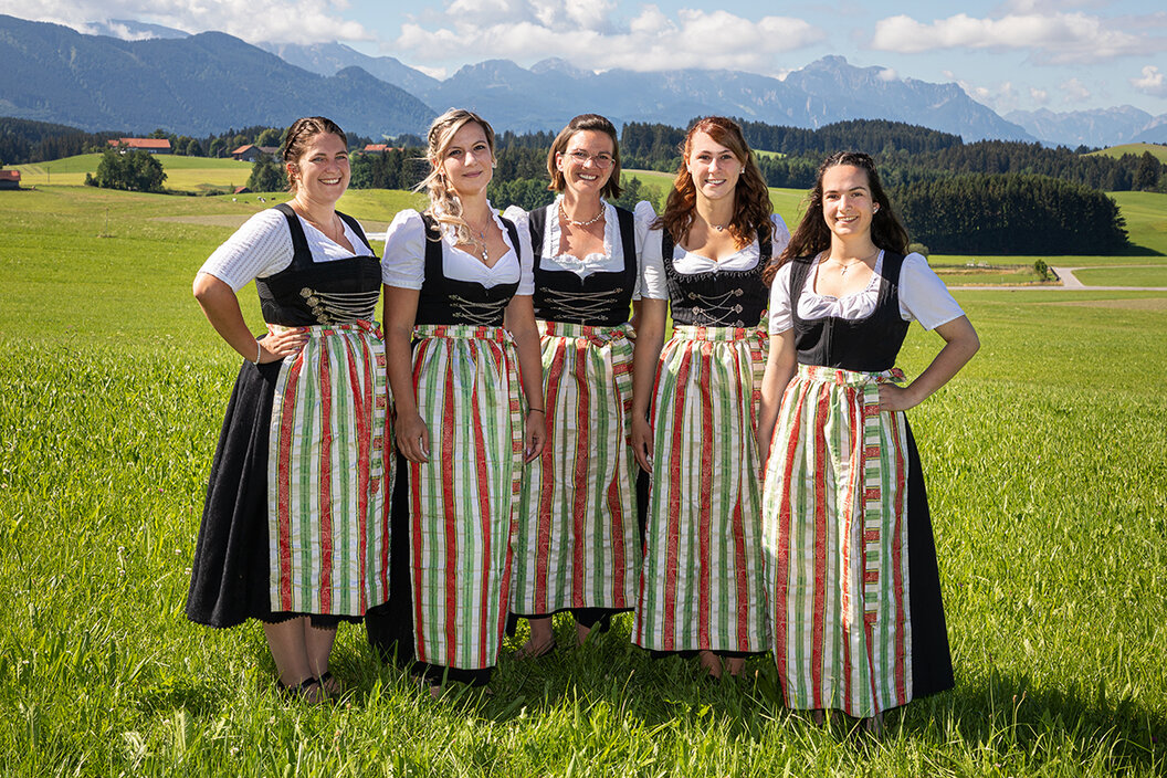 Teambild der Versandabteilung auf einer bunten Blumenwiese mit Blick in die Berge