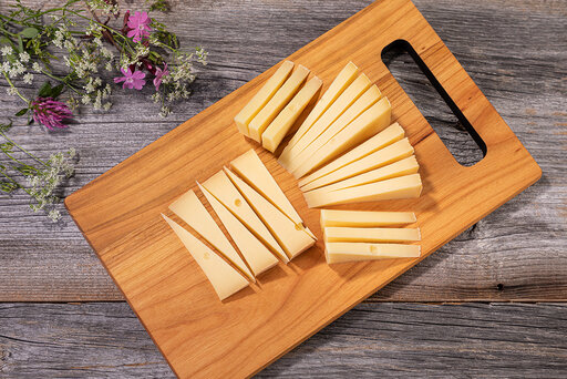Fertig geschnittener Käse auf einem Holzbrett schön hingelegt. Käse richtig schneiden.