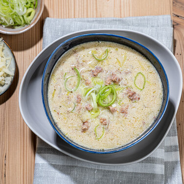 Käse Lauch Suppe verfeinert mit Hackfleisch in einer Schüssel und verziert mit Lauch