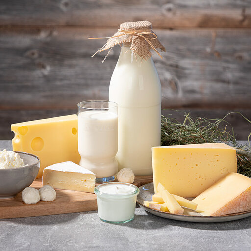 leckere Brotzeit mit einem Glas Heumilch und verschiedenen Käsespezialitäten auf einem Holzbrett verziert mit Heu