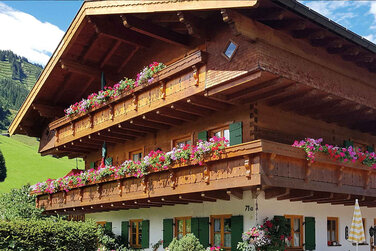 großes uriges Bauernhaus mit vielen bunten Balkonblumen und grünen Fensterläden. Vom Balkon aus einen herrlichen Ausblick in die prächtigen Berge