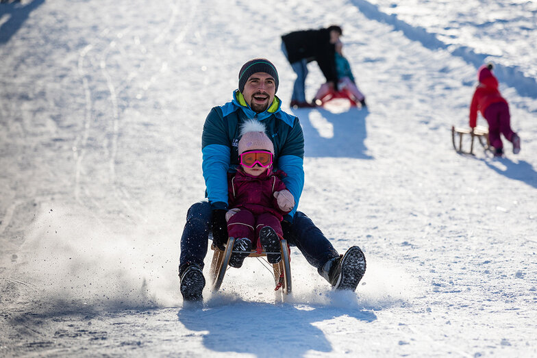 Vater und Tochter auf der Rodelbahn in schöner Winterlandschaft bei der Max-Wild-Arena in Isny