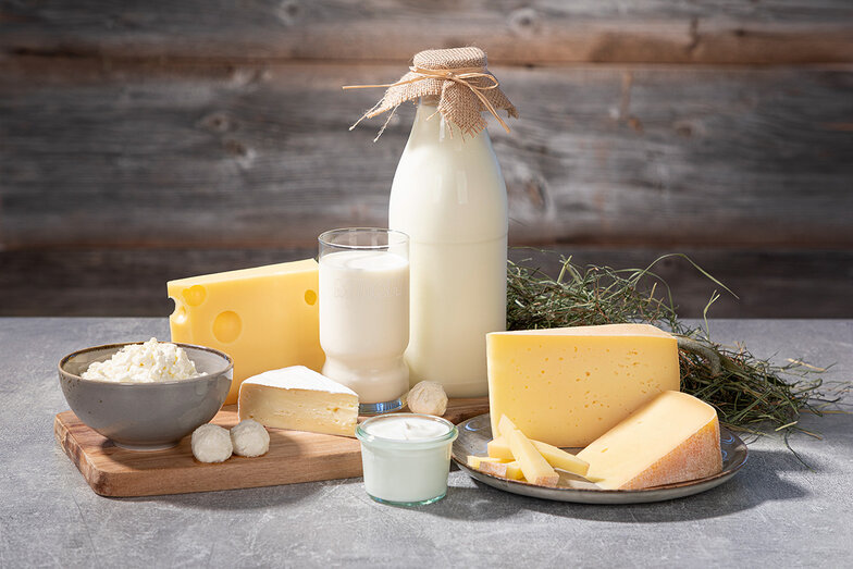 verschiedene Käse und Milch Spezialitäten auf einem Holzbrett verziert mit Heu