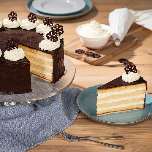 Eine ansprechende Torte mit Almbutter von der Schönegger Käse Alm gefüllt mit Sahneschichten Ein Stück herausgeschnitten auf einem Teller präsentiert