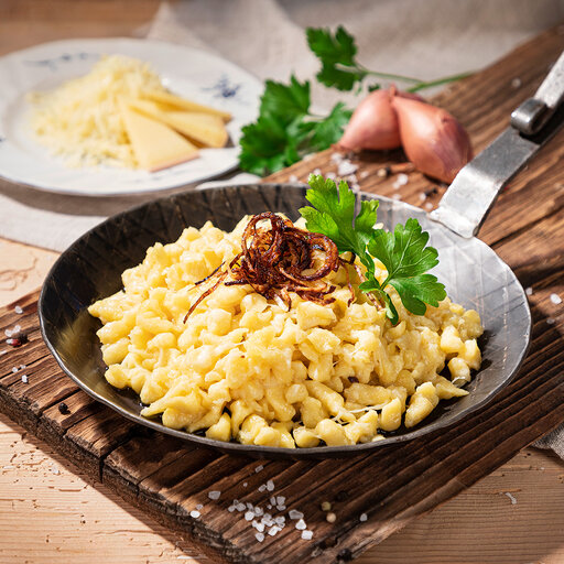 traditionelle Kässpatzen aus dem Allgäu in einer Pfanne und mit gerösteten Zwiebeln verfeinert