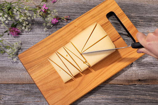Käse in Dreiecke geschnitten auf einem Holzbrett. Wie schneide ich Käse richtig.