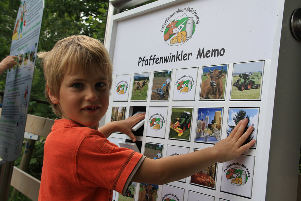 kleiner Bub der am Pfaffenwinkler Milchweg Landwirtschaftsmemory an der großen Tafel spielt