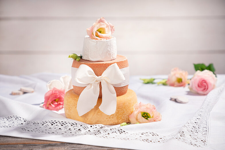 Kleine Käsetorte. Käselaibe übereinander verziert mit Rosen und einer Schleife.