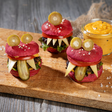 Kleine Süße Rosa Mini Monster Burger mit einem Dip daneben auf einem Holzbrett präsentiert